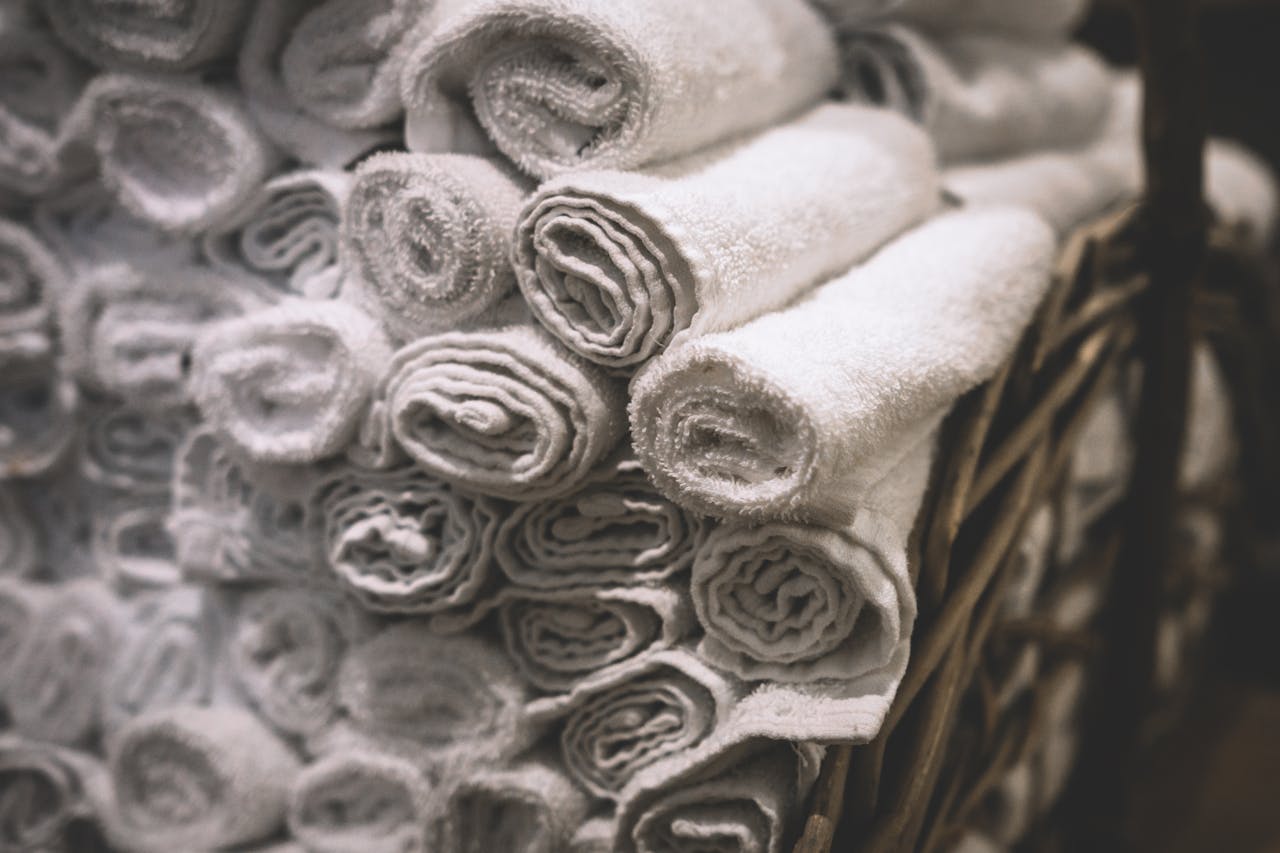 portfolio-05 Stack of neatly rolled white towels in a woven basket, perfect for spa or bathroom settings.